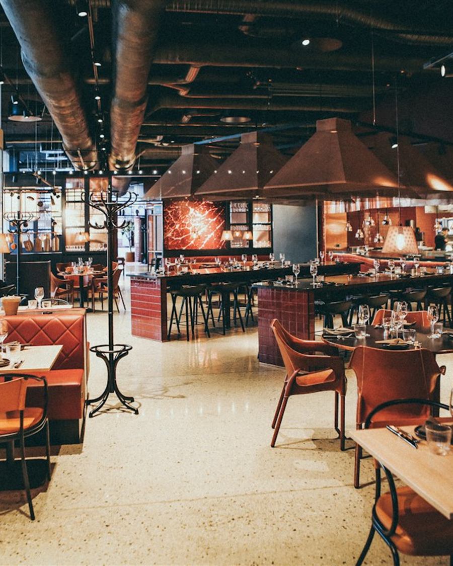 Salão de uma churrascaria com mesas e iluminação aconchegante